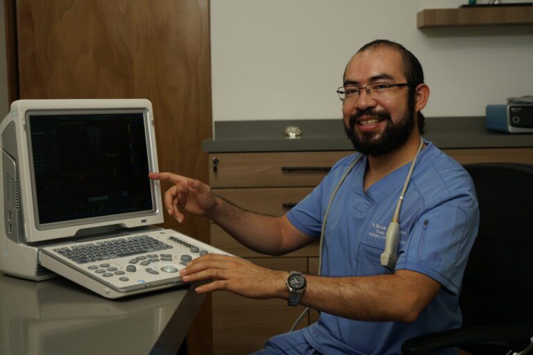 El Dr. Riky Luis Pérez Lucas, cirujano vascular, realizando un diagnóstico preciso con ultrasonido Doppler en su consultorio en Monterrey.